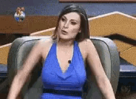 a woman in a blue dress is sitting in a chair .