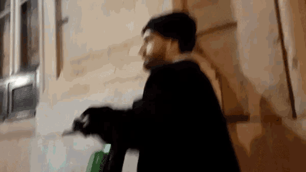 a blurry picture of a man in a black coat standing in front of a building