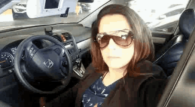 a woman wearing sunglasses is sitting in a car .