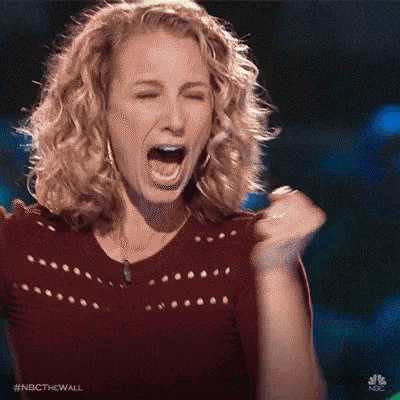 a woman is covering her ears with her hands and screaming .