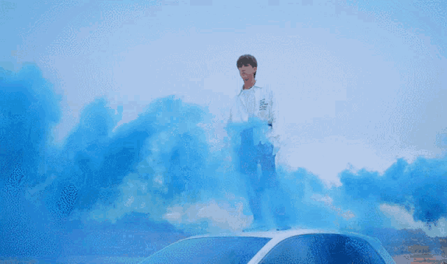 a man standing on top of a white car with blue smoke coming out of it