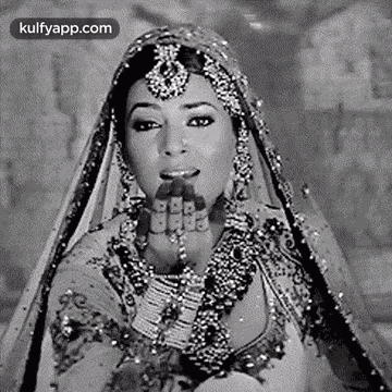 a black and white photo of a woman wearing a veil and jewelry .