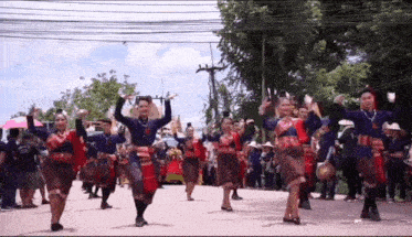 a group of people are dancing in a parade in a street