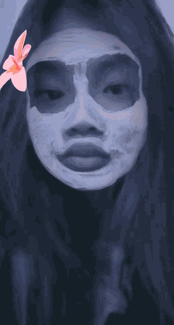 a girl with a mask on her face with a pink flower in the background