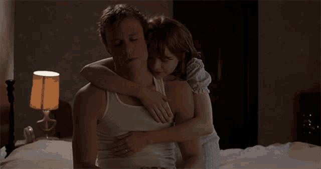 a woman is hugging a man on a bed in a dark room