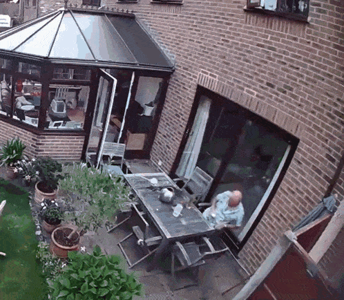 a man sits at a table in the backyard of a house