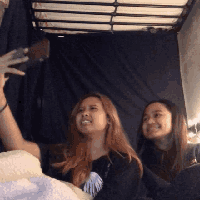 a girl taking a picture of herself with another girl