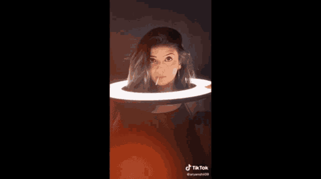 a woman is standing in front of a ring light .