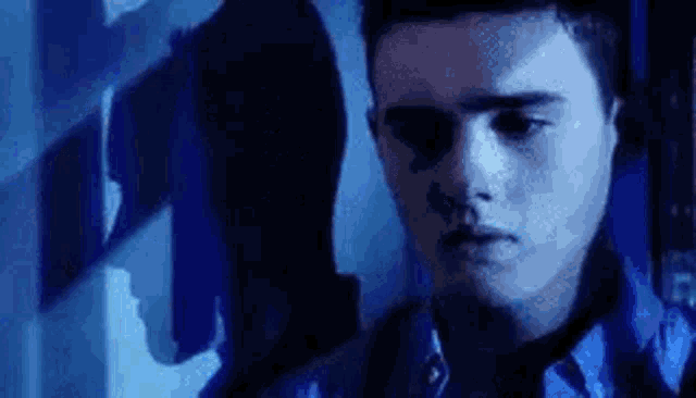 a man in a blue shirt is standing in front of a blue wall .