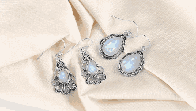 three pairs of earrings are sitting on a piece of cloth