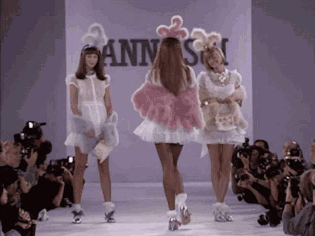 three women are walking down a runway in front of a sign that says annisa