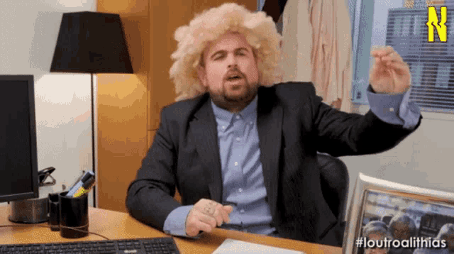 a man in a suit and wig is sitting at a desk with the hashtag #louroalithias