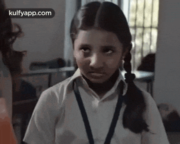 a young girl in a school uniform is looking at the camera with a serious look on her face .
