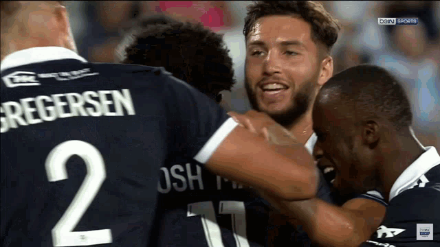 a group of soccer players are hugging and one of them has the number 2 on his back