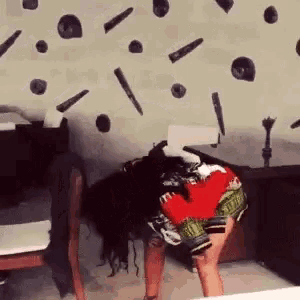 a woman is bending over in front of a wall with bullets painted on it