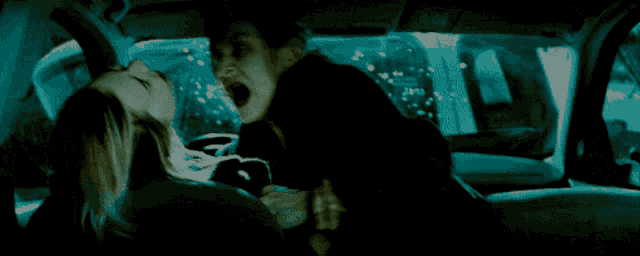 a man and a woman are kissing in a dark room with their mouths open .