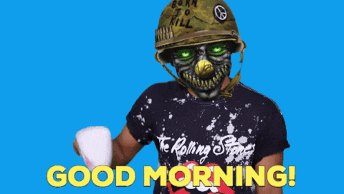 a man wearing a helmet and a rolling stones shirt holds a cup and says good morning