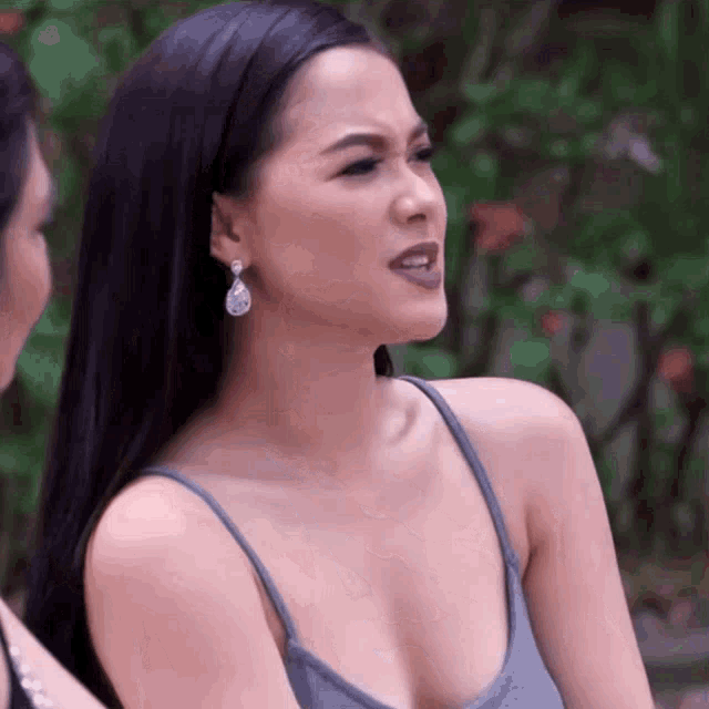 a woman in a gray tank top and earrings is talking to another woman .