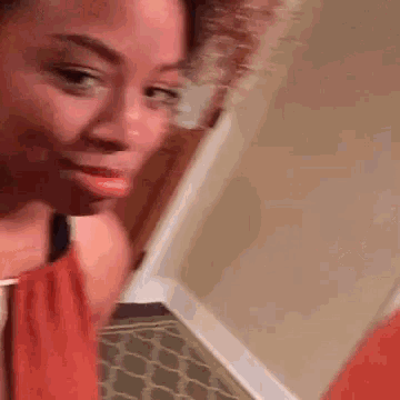 a woman is standing in a hallway with a brush in her hand and making a funny face .