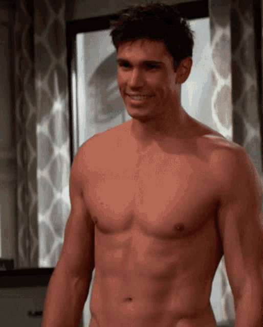 a shirtless man is standing in front of a window