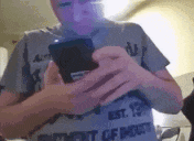 a person is holding a cell phone in their hands and wearing a t-shirt that says " est . "