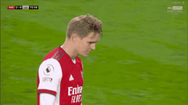 a soccer player wearing a red emirates fly iep shirt