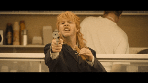 a man in a suit is pointing a gun at someone