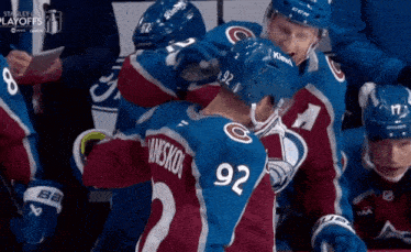 a hockey player with the number 92 on his jersey is hugging another player