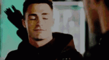 a man with his eyes closed is standing next to another man with a arrow in his back .
