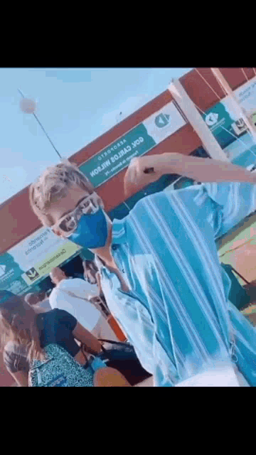 a man wearing a blue mask and sunglasses stands in front of a sign that says ' avenida ' on it