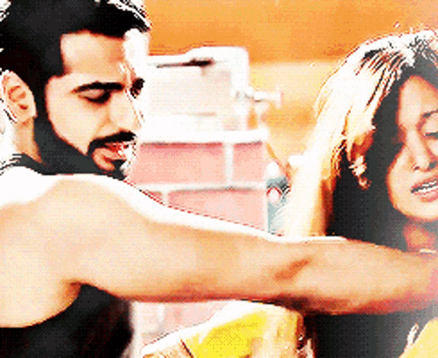 a man with a beard is holding a woman 's arm