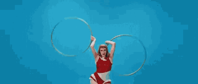a woman is holding two hula hoops in her hands .