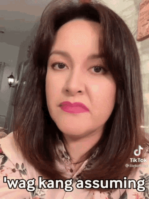 a woman wearing pink lipstick is making a funny face with the words wag kang assuming written on her face .