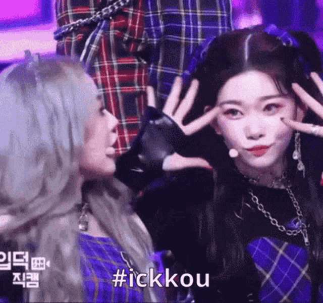 a couple of girls are standing next to each other on a stage and one of them is making a funny face .
