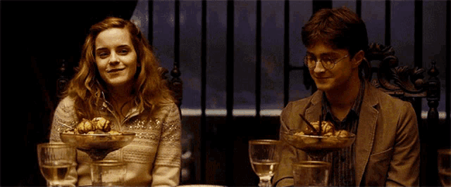 a man and a woman sit at a table with bowls of food
