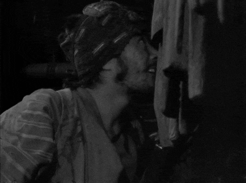 a black and white photo of a man and a woman kissing