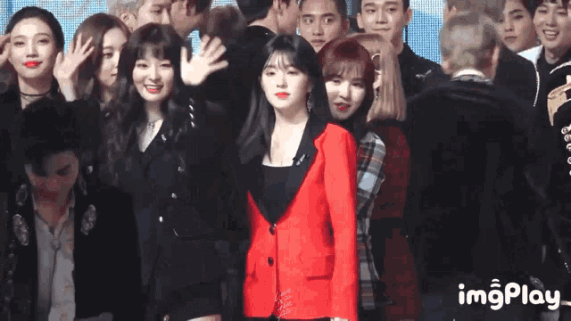 a woman in a red jacket is standing in front of a crowd .
