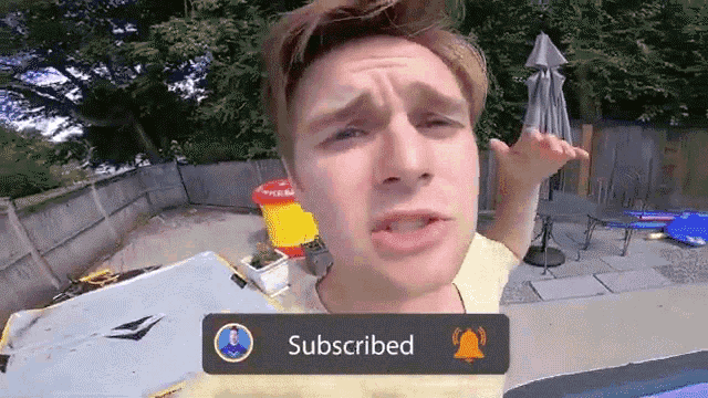 a man in a yellow shirt is standing in a backyard with a sign that says subscribed
