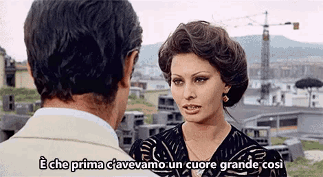 a man and a woman are talking and the woman is saying " e che prima c'avevamo un cuore grande cosi "