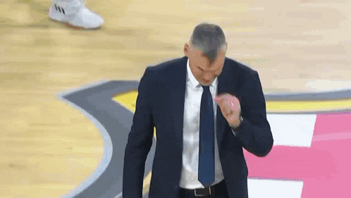 a man in a suit and tie is on a basketball court