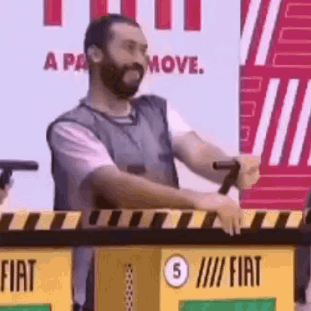 a man with a beard is sitting at a table with a sign that says fiat on it .