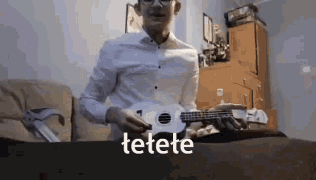 a man in a white shirt is playing an ukulele and the word tetete is visible in the corner