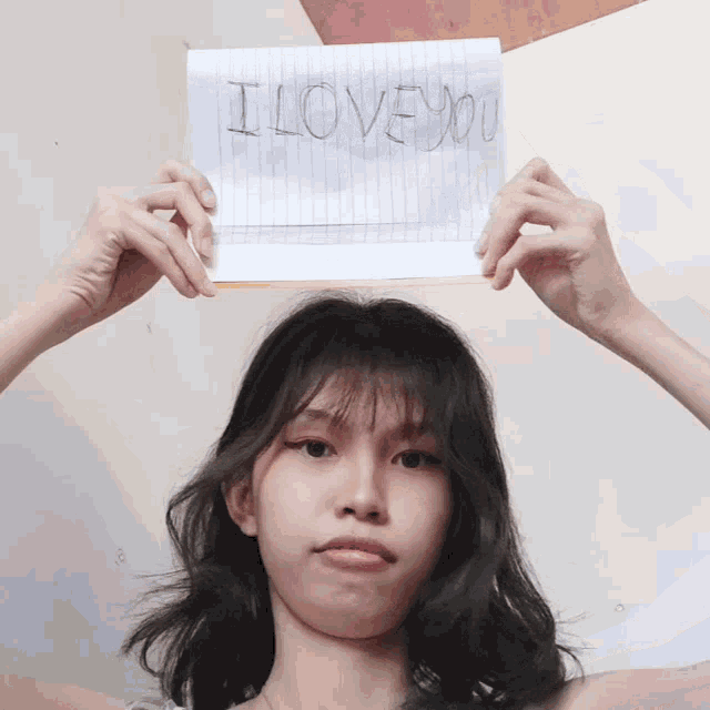a girl holds a piece of paper that says i love you