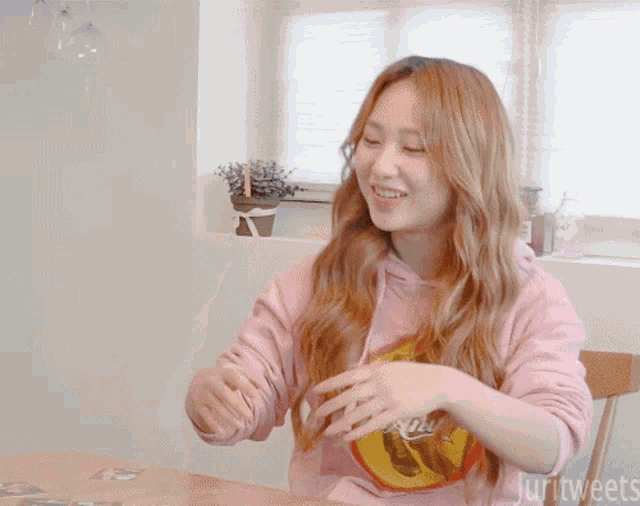a woman wearing a pink sweatshirt that says juri tweets