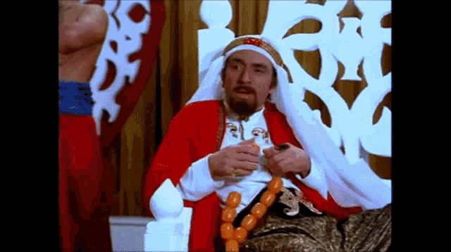 a man with a beard is sitting on a throne holding a glass of wine .