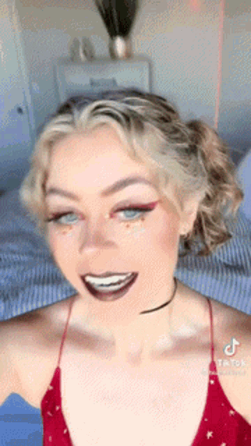 a woman in a red top is smiling and taking a selfie with her phone .