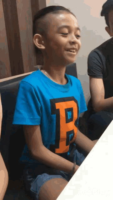 a boy in a blue shirt with the letter p on it