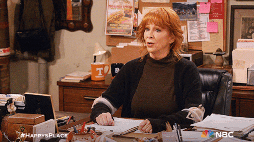 a woman sits at a desk with a nbc logo on the bottom