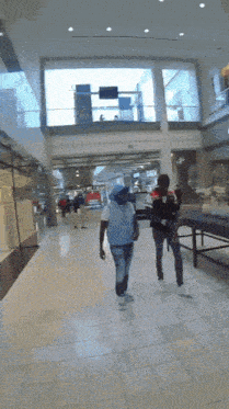 a man in a white shirt is walking down a hallway