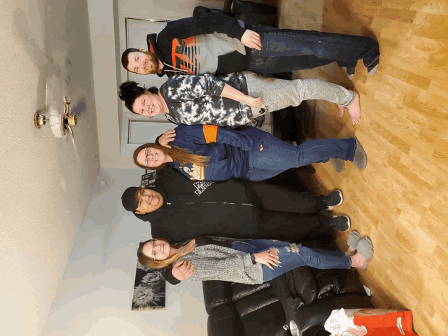 a group of people posing for a picture including one wearing a tie dye hoodie